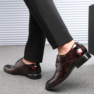 Nahaufnahme glänzender Herrenschuhe in Burgund mit Blumenmuster und Spitze vorne