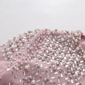 Close-up detail of pink heavy industry garment with pearls and sparkling rhinestones