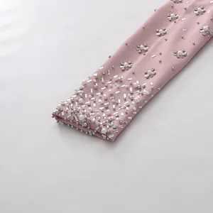 Detailed close-up of elegant pink sleeve featuring heavy pearl and rhinestone embellishments.