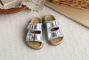 Detalle de sandalias estilo Birkenstock plateadas metálicas para niña con flecos grises