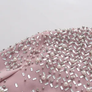 Detailed close-up showing heavy rhinestone and pearl embroidery on elegant pink fabric