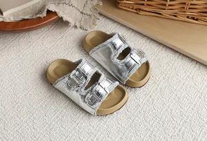 Detalle de chanclas plateadas para niña con flecos y tiras de doble hebilla