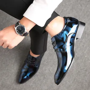 Detail von blau gemusterten glänzenden Lederschuhen mit spitzer Kappe und Schnürung.