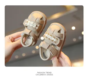 Dettaglio dei sandali beige per bambini con punta chiusa, suole morbide e chiusura a strappo.