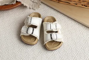 Detalle de sandalias tipo Birkenstock para niños en blanco con flecos y hebillas de metal