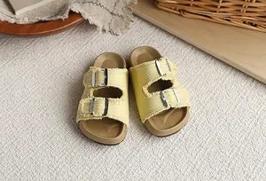 Primer plano de sandalias Birkenstock amarillas para niños con flecos y hebillas de metal