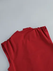Close-up detail of red sleeveless dress featuring elegant pleated shoulder design.