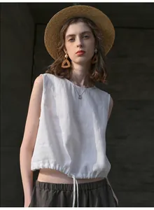 Gedetailleerde opname van een witte mouwloze linnen crop top met trekkoord bij de zoom.