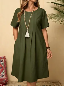 Détail d'une robe en coton et lin vert foncé avec des poches et des plis sur le devant