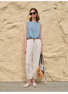 Casual zomeroutfit met blauwe mouwloze top met trekkoord en witte linnen broek