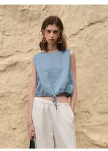 Detail van een mouwloze blauwe linnen crop top met verstelbaar trekkoord in de zoom