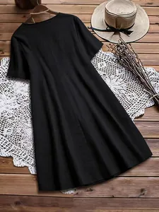 Vue arrière d'une robe noire en coton et lin avec un chapeau de paille rétro sur bois