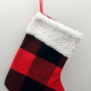 Detail view of a red and black buffalo plaid Christmas stocking with white faux fur cuff.