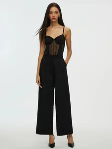 Detailed shot of a sexy black mesh bodysuit paired with elegant high-waisted trousers