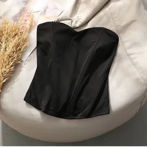 Detail of black corset tube top with boning structure on beige background