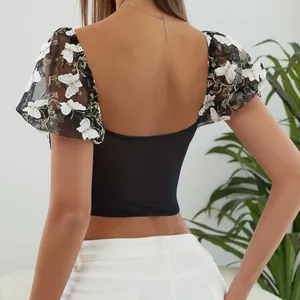 Vista trasera de crop top de malla negra con elegante bordado de mariposas blancas.