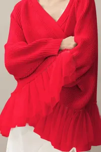 Close-up of red knit sweater featuring delicate mesh ruffle hem and V-neckline details