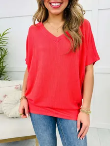 Detail shot of a women's casual loose-fit V-neck ribbed t-shirt in bright coral orange