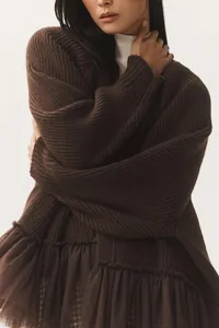 Close-up of brown knit sweater featuring delicate mesh ruffle hem and ribbed texture.