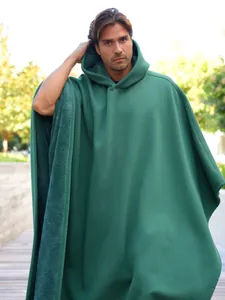 Dettaglio del poncho verde oversize con cappuccio e fodera in pile calda per inverno