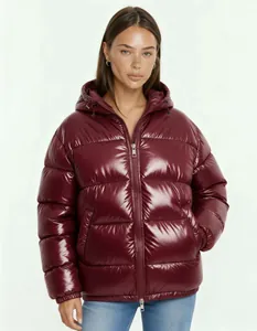 Primo piano di donna che indossa un piumino con cappuccio bordeaux lucido con zip in metallo.