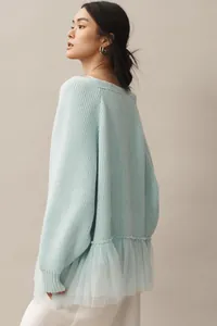 Side view of mint green knit sweater featuring a layered tulle ruffle hemline.