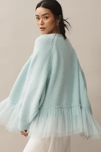 Close-up detail of the light blue knit sweater featuring a stylish tulle ruffle hem design