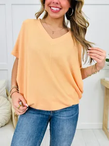 Close-up of women's peach V-neck ribbed t-shirt showing detailed fabric texture.