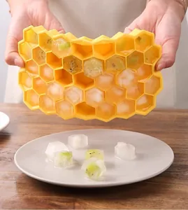 Dettaglio del vassoio per cubetti di ghiaccio in silicone a nido d'ape con stampo giallo e frutta.