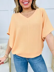 Close-up detail of a women's peach V-neck ribbed casual loose short sleeve T-shirt.