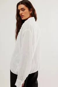 Detail view of white linen shirt featuring delicate lace trim and breathable fabric texture.