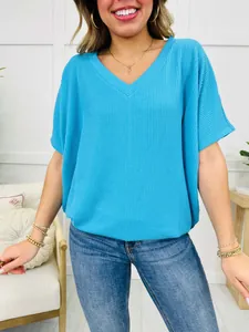 Close-up view of a blue V-neck ribbed T-shirt showing fabric texture and loose fit