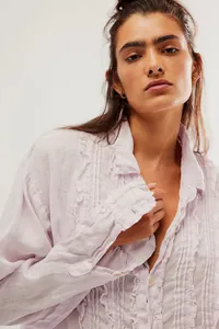 Close-up detail of delicate ruffles and linen texture on a pink long sleeve shirt.