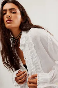 Detail shot of white cotton linen shirt featuring delicate ruffle trim and pleats.