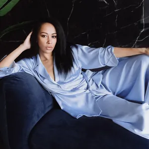 Elegant light blue satin pajama set for women featuring a robe and pants in a luxury home setting