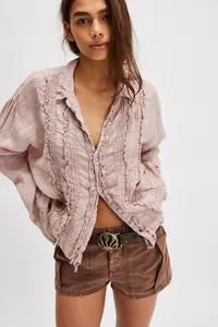 Detailed close-up view of a bohemian dusty rose linen shirt with ruffled lace trim