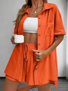 Stylish orange two-piece summer set with short sleeve shirt and drawstring shorts.