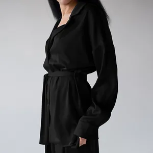 Close-up detail of luxurious black faux silk women's pajama set with waist belt