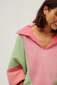 Close-up van de zachte textuur en V-hals kraag op het roze en groene color-block fleece sweatshirt
