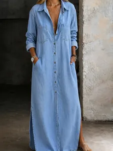 Detailed view of long light blue denim shirt dress featuring buttons and side slits
