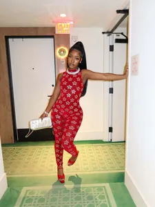 Modell trägt roten ärmellosen Netz-Jumpsuit mit goldenen Sternmustern im Hotelflur