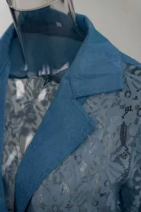 Gedetailleerde opname van een blauwe denim blazer met verfijnde kanten bloemeninzet