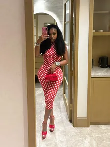 Elegante donna con tuta all'americana a pois rossi e bianchi in un selfie allo specchio