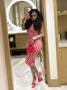 Foto lifestyle di una tuta intera rossa a pois con scollo all'americana su modella.