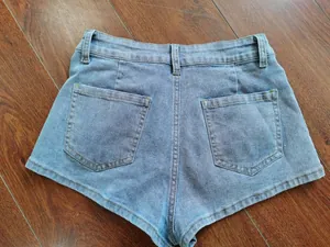 Detailed back view of light blue denim shorts with two pockets on wooden floor.