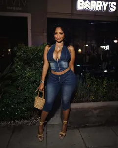 Donna in elegante set top halter e pantaloni capri in denim blu in strada di notte