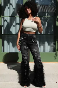 Detail view of black denim featuring distressed textures, pearl beads, and feather cuffs