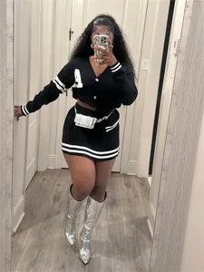 Stylish varsity style black two-piece knit cardigan and mini skirt set on a model