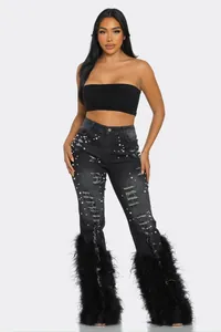 Detailed view of high-waist distressed black denim jeans with pearls and feather trim