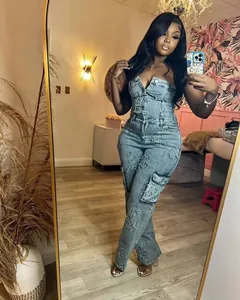 Full body view of a woman wearing a strapless denim jumpsuit with cross embroidery.